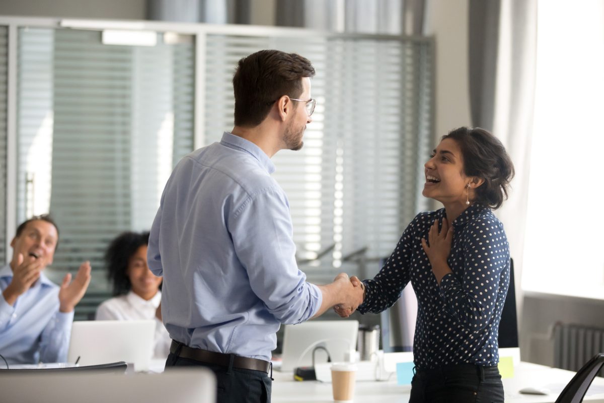 Team leader motivating handshaking female indian employee